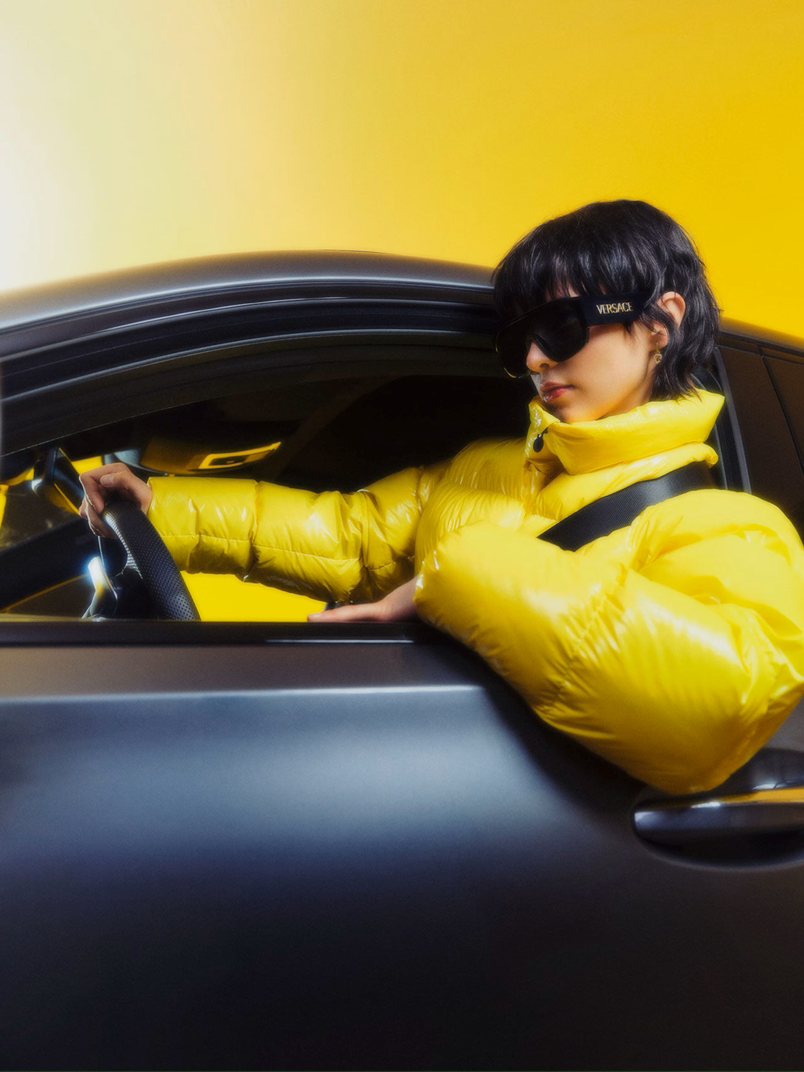 Mercedes-Benz Fashion Week 2024 A woman in a white gown and a man standing behind in a sleeveless top and white pants with a sculpture behind featuring the Mercedes-Benz logo
